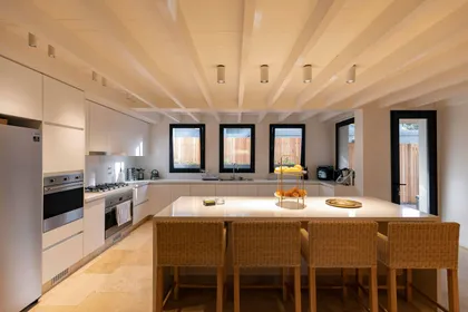 Cocina moderna-rústica con isla grande y vigas de madera expuestas — proyecto Las Marías, por Santiago Cordeyro Arquitectos, en San Isidro