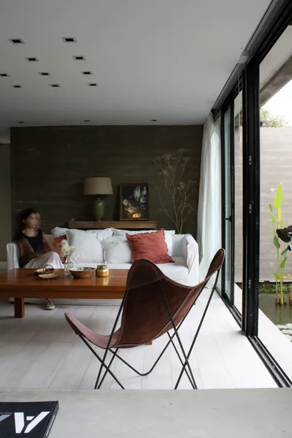Living moderno con sillón butterfly y pared texturizada oscura — proyecto ampliacion NJ, por arquitectura.JD, en City Bell
