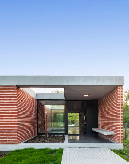 Fachada moderna de casa con ladrillo expuesto y hormigón — proyecto Casa FLOIG, por V2 Arquitectos, en Villa Elisa