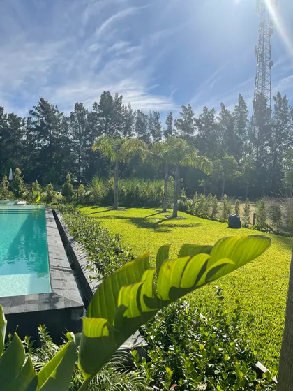 Piscina infinita en jardín exuberante con torre de telecomunicaciones — proyecto ALBANUEVA, por Baires Green, en B1648 Tigre
