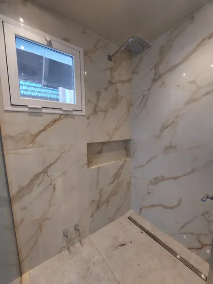 Baño moderno con paredes de mármol y ducha empotrada en techo — proyecto Reforma Interior - Village, por CM Espacio & Arquitectura, en Pilar