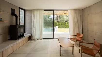 Sala moderna de hormigón con grandes ventanales y piscina — proyecto CASA CC, por Rastro Estudio, en San Isidro
