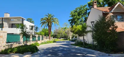 Calle residencial con casas modernas y vegetación exuberante — proyecto Finca Sarmiento, por Estudio Rifahi, en Martínez
