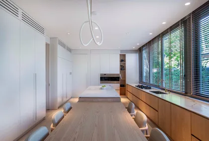 Cocina moderna con isla y mesa larga de comedor, iluminación indirecta — proyecto Casa Magnolia, por Estudio PK, en San Isidro