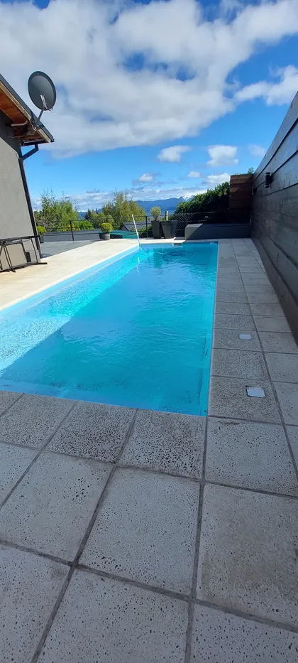 Pileta moderna con vista a las montañas y patio de piedra — proyecto Piscina Climatizada, por ARM ARQUITECTOS, en San Carlos de Bariloche