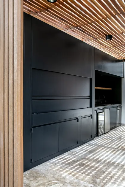 Cocina exterior moderna con techo de listones de madera y muebles negros — proyecto Obra La Posta, por Arq. Lourdes Yarade Saravia, en Pilar