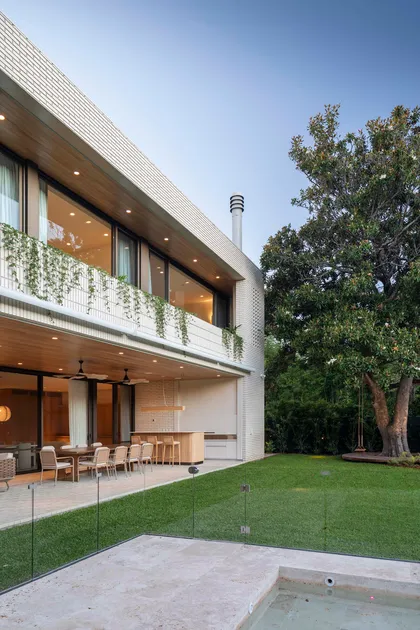 Casa moderna con fachada de ladrillo blanco texturizado y jardín exuberante — proyecto Casa Magnolia, por Estudio PK, en San Isidro