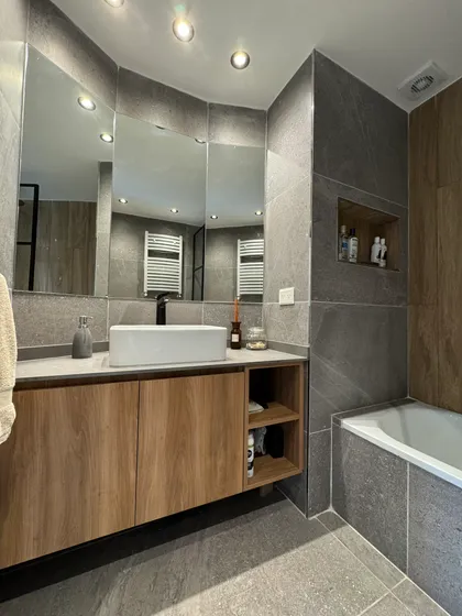Baño moderno con vanitory de madera, espejo grande y ducha de piedra — proyecto Salguero II, por MDBK Arquitectura, en Palermo