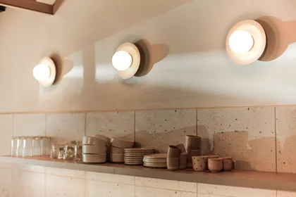Cocina minimalista con luces de pared texturizadas y almacenamiento integrado — proyecto La Selva Yoga - Cafe, por Jeitinho Estudió Creativo, en La Plata