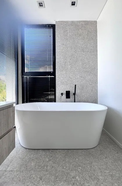 Baño moderno minimalista con bañera exenta blanca y paredes de piedra gris — proyecto DISEÑO INTERIOR - SAN BENITO - BAÑO SUITE , por FOCO_arquitectura&diseñointerior, en Belén de