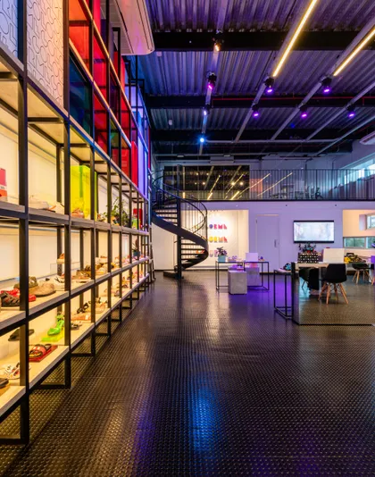Oficina industrial moderna con escalera espiral y iluminación LED multicolor — proyecto Showroom Melissa, por Pricila Dalzochio