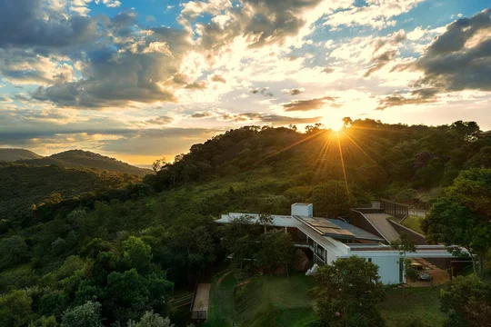 Casa contemporánea sobre montaña con piscina al atardecer dorado — proyecto Casa das Pedras, por Tetro Arquitetura