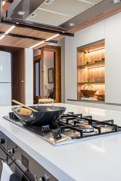 Cocina moderna con isla, anafe integrado y muebles de madera — proyecto Casa Nordelta, por Gutman+Lehrer Arquitectas, en Nordelta