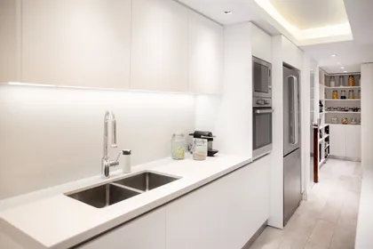 Cocina minimalista moderna con muebles blancos y mesada de piedra — proyecto Libertador , por Estudio Basa, en CABA