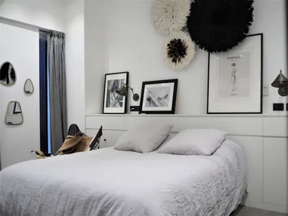Dormitorio minimalista blanco con arte y almacenamiento incorporado — proyecto Loft Godoy Cruz, por Estudio 8.66, en Palermo