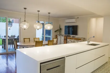 Cocina moderna de concepto abierto con isla grande y luces colgantes — proyecto Casa Estilo Francés, por Estudio Fernandez Long & asoc., en Martínez