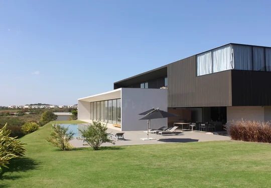 Casa contemporánea con fachada mixta, pileta y jardín abierto — proyecto Residência JY, por Gil Fialho