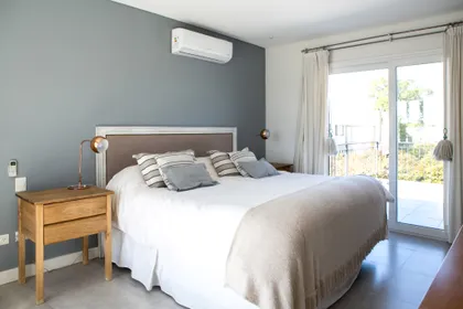 Dormitorio moderno con pared gris, cama doble y mesas de luz de madera — proyecto Ayres Plaza, por ATO Arquitectos, en Ayres Plaza