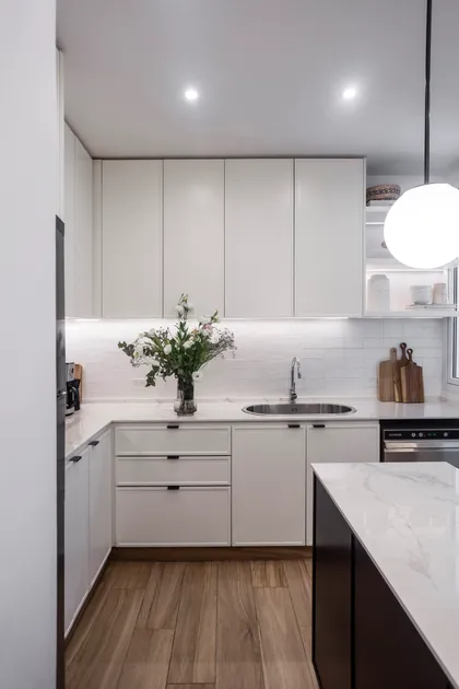 Cocina moderna minimalista con isla, gabinetes blancos y luz colgante esférica — proyecto Bustamante, por JT ARQUITECTURA, en Buenos Aires