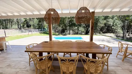 Comedor rústico exterior con mesa de madera y sillas de ratán — proyecto Casa Luvir - Barrio Costa Esmeralda (Partido de la Costa, Buenos Aires) German S, por German Salas arquitec