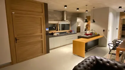 Cocina moderna con isla flotante y puerta de madera — proyecto Casa G, por TAVA Coop, en Pinamar