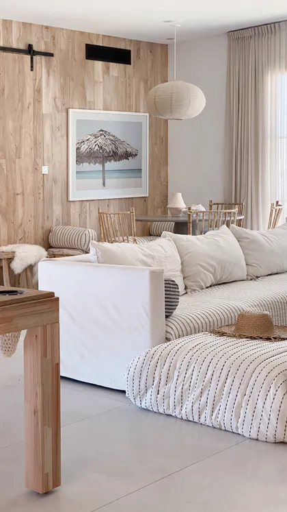 Living moderno boho con pared de madera y sofá blanco — proyecto El Refugio, por Grupo Pauta Arquitectura, en Pinamar