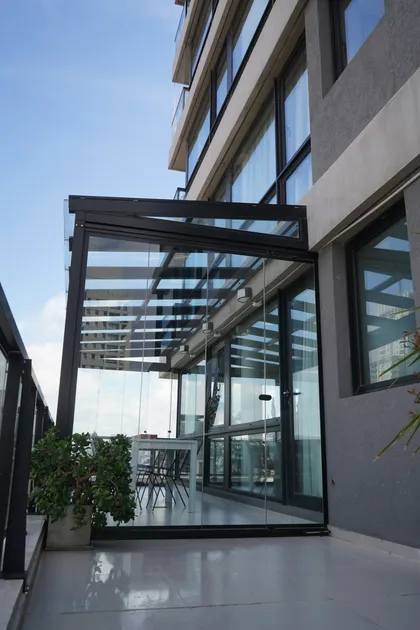 Terraza de departamento moderna con cerramiento de vidrio y techo retráctil — proyecto TOLDER - TECHOS DE VIDRIO, por Argentina en Obra 2024, en Rincón de Milberg