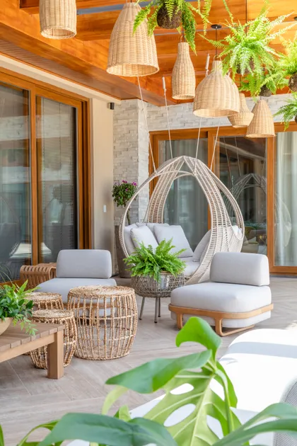 Terraza con sillón colgante y luminarias de ratán estilo boho — proyecto Projeto Destaque Club&Casa, por OKA ARQUITETURA
