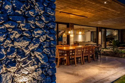 Comedor exterior rústico junto a muro de piedra con pérgola — proyecto casa la huella, por Guerrero Arquitectos, en Pinamar