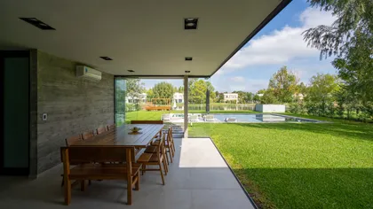 Comedor exterior moderno con césped y piscina — proyecto Casa Miralagos II, por Besonías Almeida arquitectos, en La Plata
