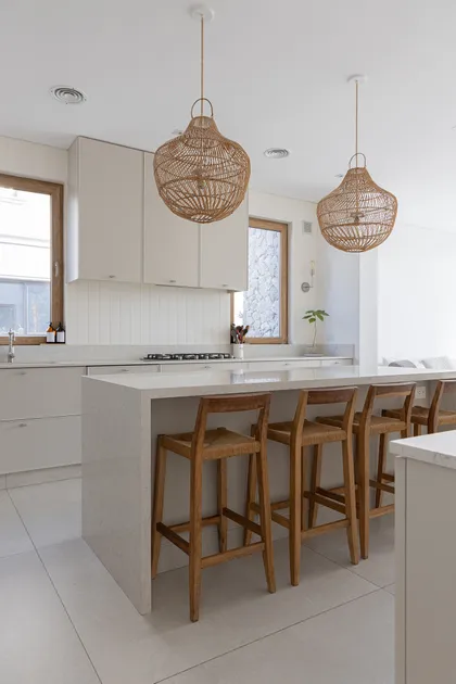 Cocina moderna con isla de piedra, bancos de madera y lámparas colgantes de mimbre — proyecto Casa Al Agua - Grupo PAUTA, por Gaby Alfonso, en Belén de Escobar