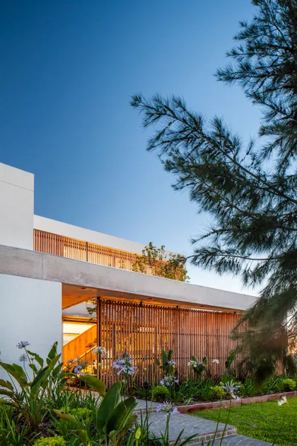 Fachada moderna con jardín exuberante y pantalla de madera — proyecto Casa Tom, por LSA. , en Belén de Escobar