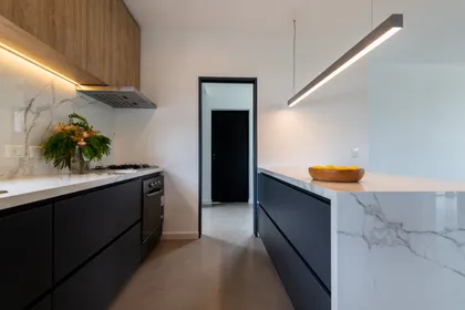 Cocina moderna con isla de mármol y gabinetes negros — proyecto Santa Isabel - Andrea Gonzalez, por ABEJA CONCEPT, en Nordelta
