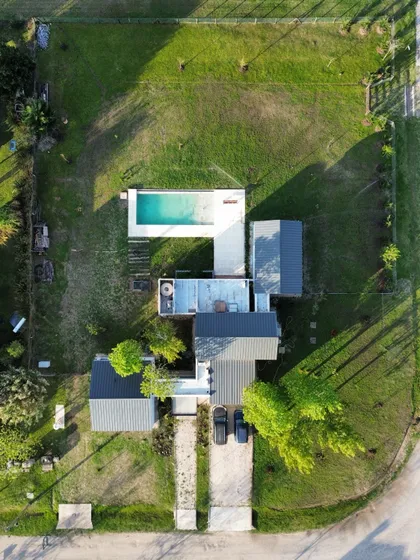 Casa moderna vista aérea con pileta turquesa y jardín verde — proyecto Casa 125, por RY Construir Estudio, en San Vicente