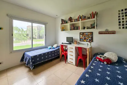 Dormitorio juvenil con dos camas, escritorio y gran ventana — proyecto San Matías, por GeN Arquitectura, en Ingeniero Maschwitz
