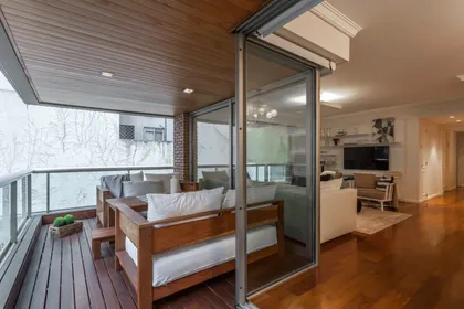 Balcón moderno con muebles de madera y vista urbana — proyecto Sucre Plaza, por C - ESTUDIO, en Buenos Aires