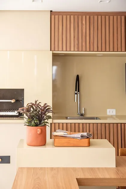 Cocina moderna con isla beige, mesada de madera y detalles en terracota — proyecto Apartamento Vila Leopoldina VIII, por Bordin E Soares Interiores