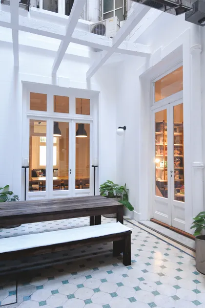 Pasillo minimalista con doble altura, puertas vidriadas y piso de mosaico — proyecto Callao, por Estudio Diez Muzzio, en CABA