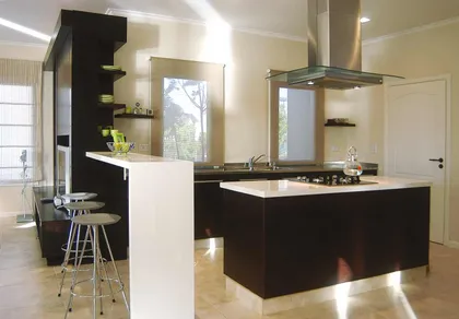 Cocina moderna con isla negra, mesada blanca y piso de madera — proyecto Santa Fe Style, por Ciba Arquitectura