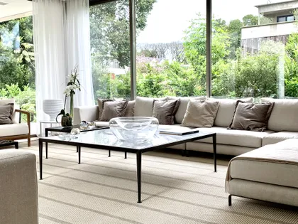 Living moderno con ventanales al bosque y sofá modular gris — proyecto CASA BECCAR, por Estudio Xime Fontan Balestra, en Béccar