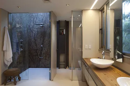 Baño moderno con ducha de piedra y vanitory de madera — proyecto Acasusso, por Remy Arquitectos, en Acassuso