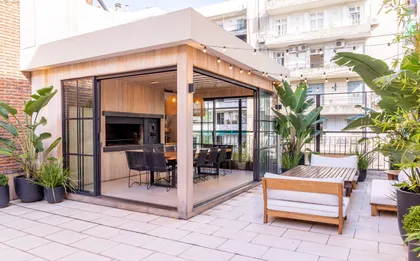 Quincho moderno con deck, parrilla y muebles de madera al aire libre — proyecto Terraza en la ciudad, por Casa Cunia, en CABA