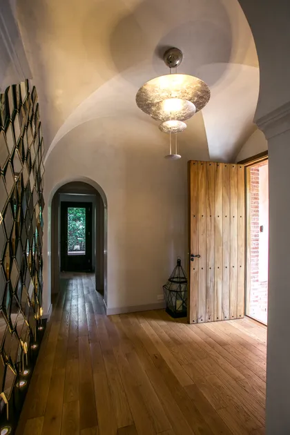 Pasillo moderno con bóveda blanca, piso de madera y puerta artesanal — proyecto CasaLA, por Ricardo Pereyra Iraola