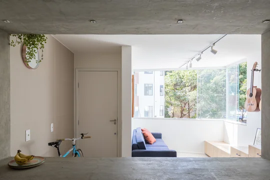 Pasillo minimalista con doble altura, ventanal grande y piso de hormigón pulido — proyecto Apartamento 407N, por Coda Arquitetos