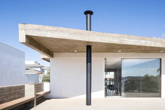 Terraza moderna con piso de hormigón, ventanal vidriado y chimenea negra — proyecto Casa Bentes, por Coda Arquitetos