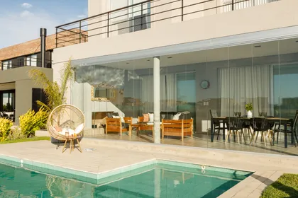 Terraza moderna con piscina y muebles de rattan — proyecto TOLDER - CERRAMIENTOS, por Argentina en Obra 2024, en Rincón de Milberg