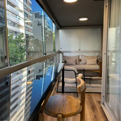 Balcón moderno con vista y muebles de madera y tela — proyecto Salguero I, por MDBK Arquitectura, en Palermo