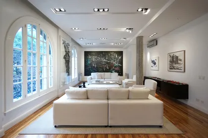 Living moderno con sofá blanco y grandes ventanales arqueados — proyecto DEPARTAMENTO EN PALACIO LOS PATOS, por ABAD GADANO, en Buenos Aires
