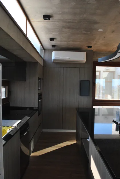 Cocina moderna minimalista con techo de hormigón y muebles grises — proyecto Casa FSC, por TAVA Coop, en Pinamar
