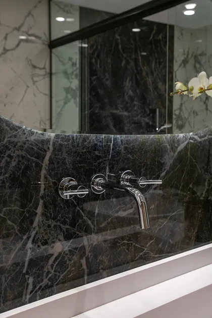 Grifo flotante cromado en pared mármol negro con veta blanca — proyecto Casa Oroño, por Estudio Plats, en Buenos Aires